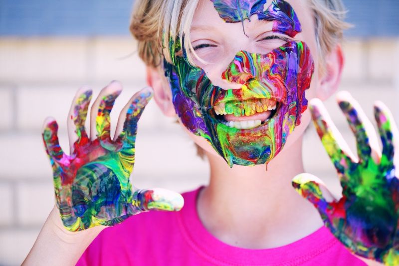 child with paint on his hands and face